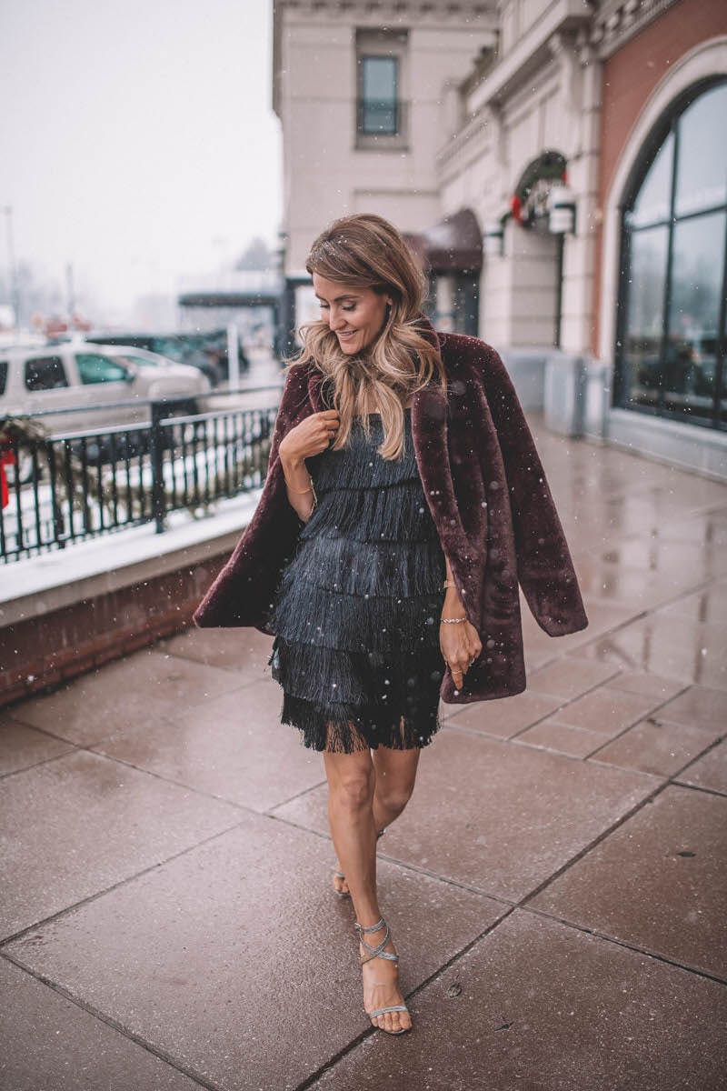 Black Fringe Dress and Fur Coat  | Holiday Party look featured by top Indianapolis fashion blogger, Karina Style Diaries: image of a woman wearing a Lesley Jane black fringe dress, Manolo Blahnik heels, Chanel bubble bag, Daniel Wellington watch and Jemma Sands drop earrings