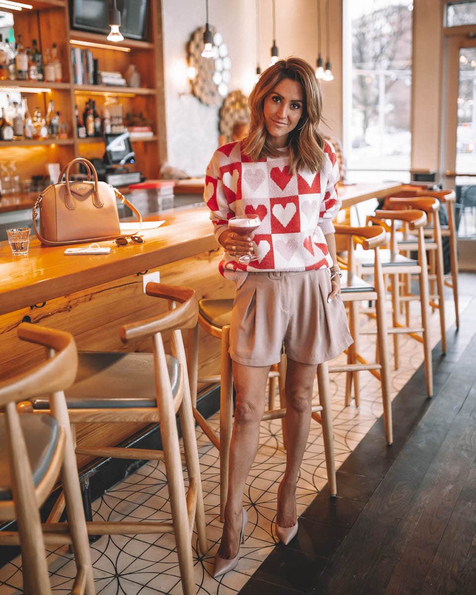 Fashion Blogger Karina Reske| Heart Pattern sweater | Valentine's day outfit | cute bar photos | Goodnight Macaroon Valentines Day sweater featured by top US fashion blogger, Karina Style Diaries: image of a woman wearing a Valentines Day sweater, Romwe shorts, Steve Madden toe pumps, Givenchy Antigona, and Ray-Ban aviator sunglasses