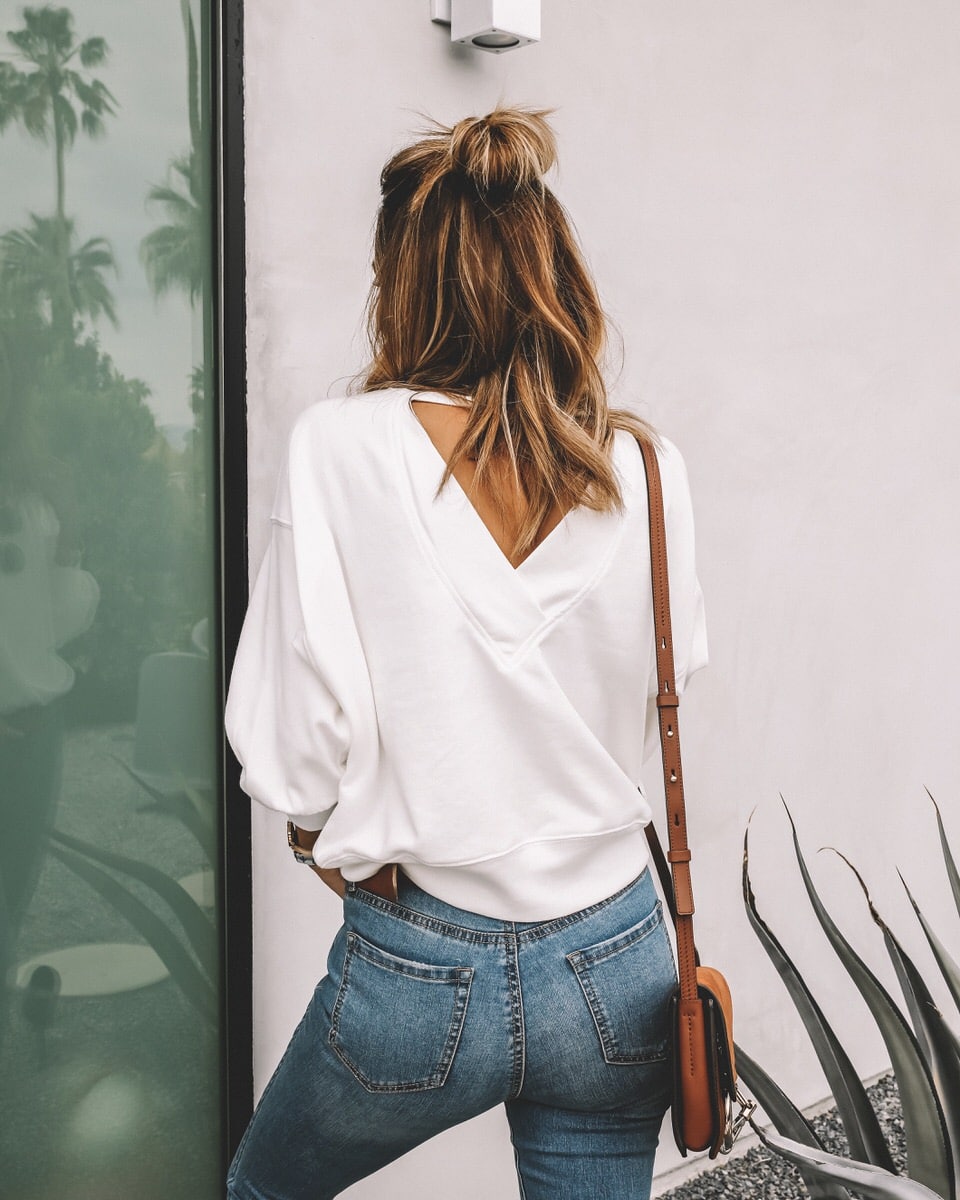 Fashion blogger Karina Reske | denim look | white sweatshirt | fringe jeans | palm leaf white earrings | travel outfit idea | Sofía Vergara Jeans