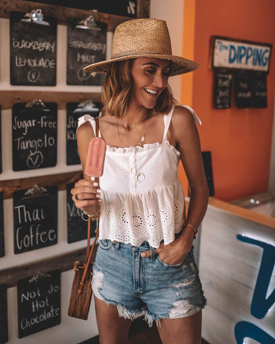 Karina Style Diaries wearing an eyelet top with tie straps hight waisted abercrombie shorts circle basket bag straw hat layerd gold necklaces