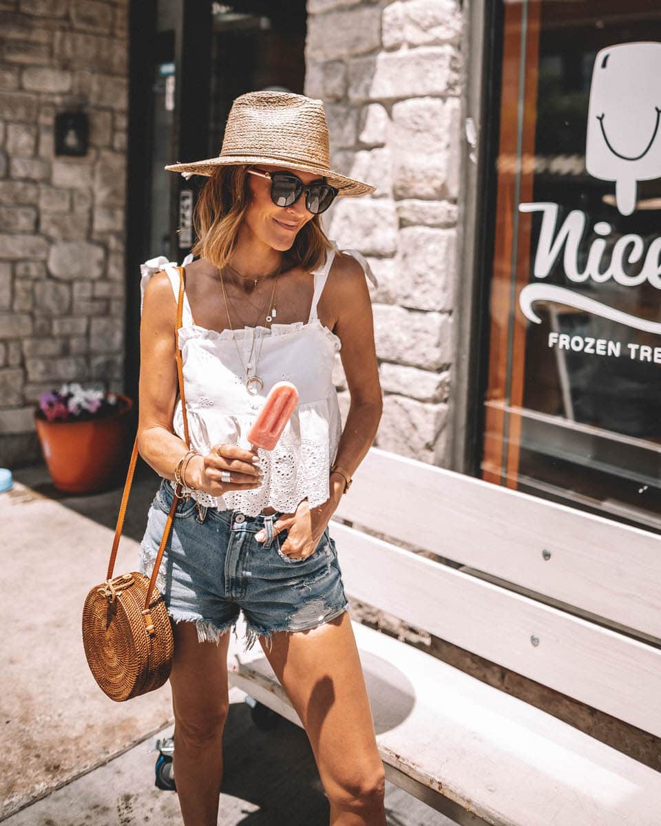 Karina Style Diaries wearing an eyelet top with tie straps hight waisted abercrombie shorts circle basket bag straw hat layerd gold necklaces