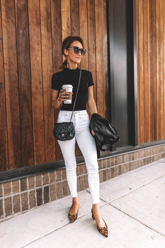 Karina Reske wearing white skinny jeans black bodysuit chanle buble crossbody leopard shoes pointy flats leather suede moto jacket black and white chic outfit idea