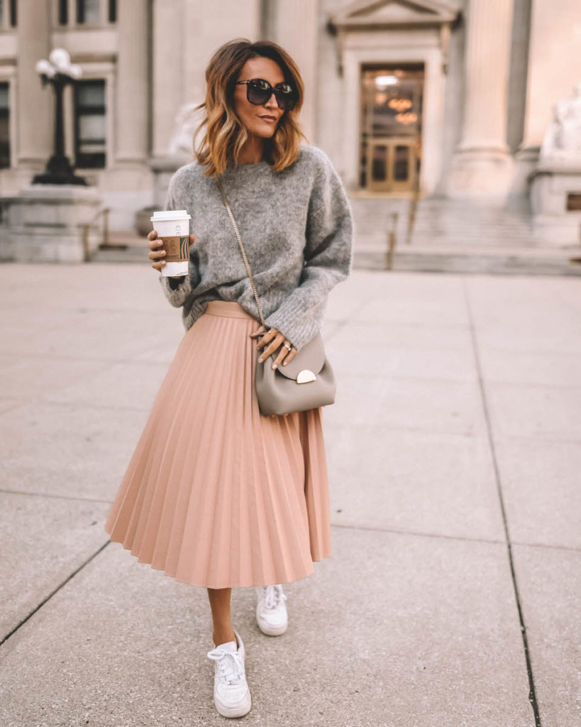 Karina Reske wearing blush pleated skirt grey sweater Polene Paris chain bag white sneakers 