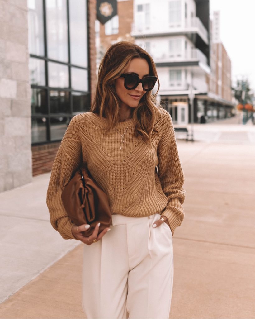 karina wears bottega pouch bag with camel sweater and white pant