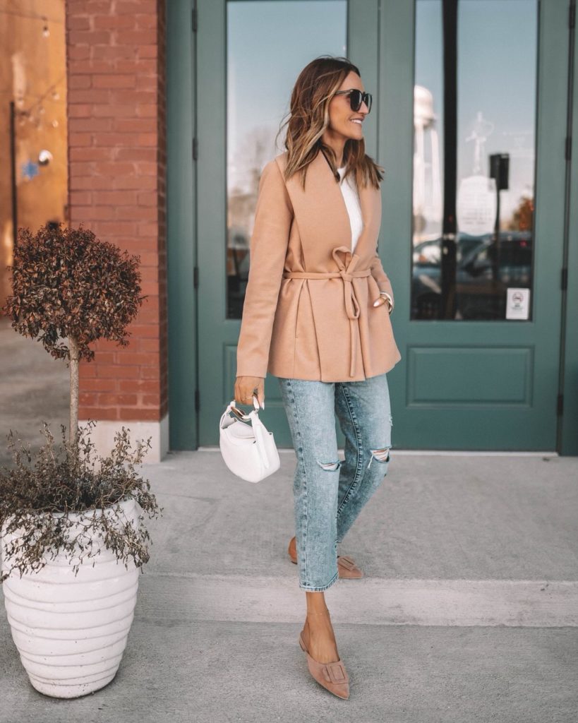 Karina wears express camel wrap coat with white sweater and straight ankle jeans