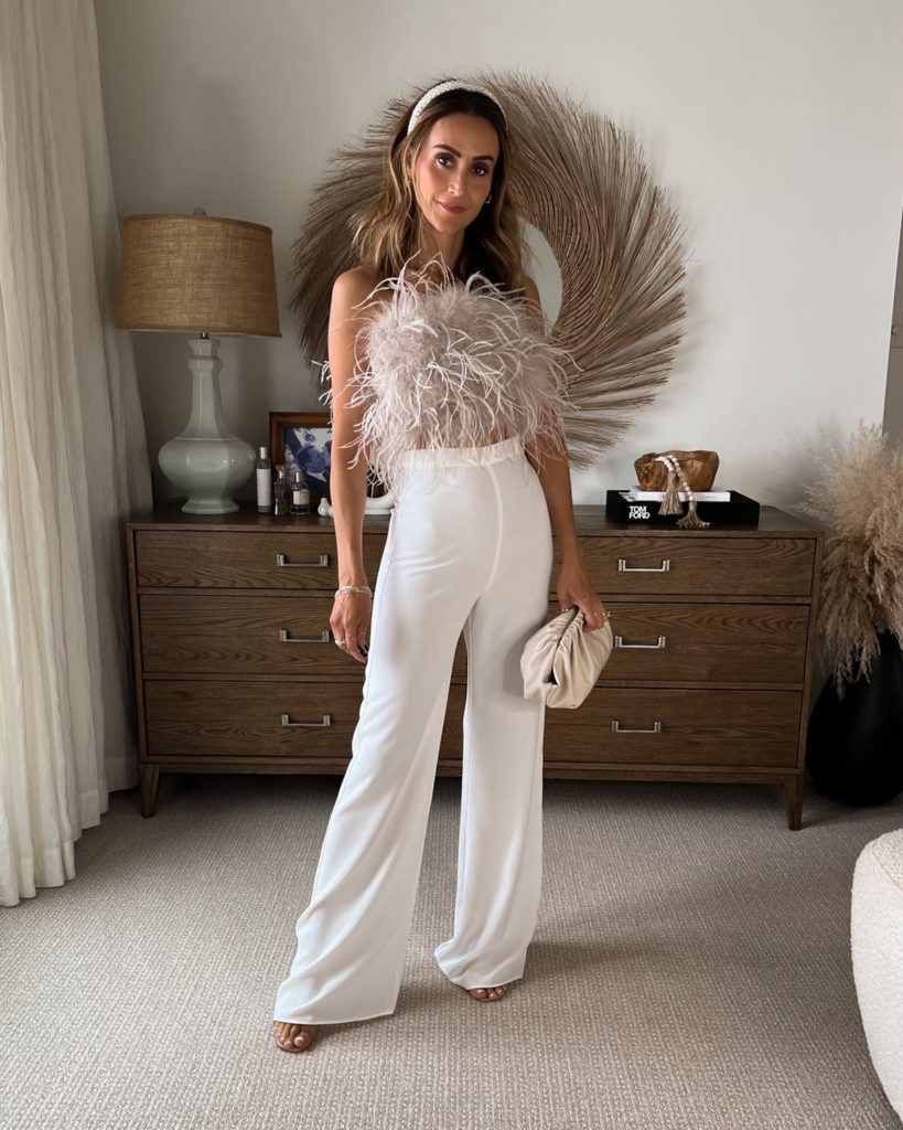 Karina wears lamarque feather top with white pants and dumpling bag