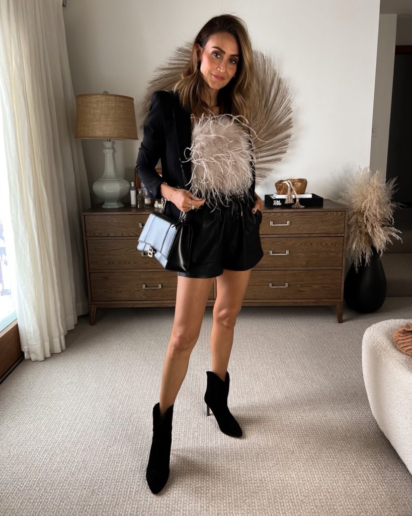 Karina wears lamarque feather top with black shorts and black jacket and booties