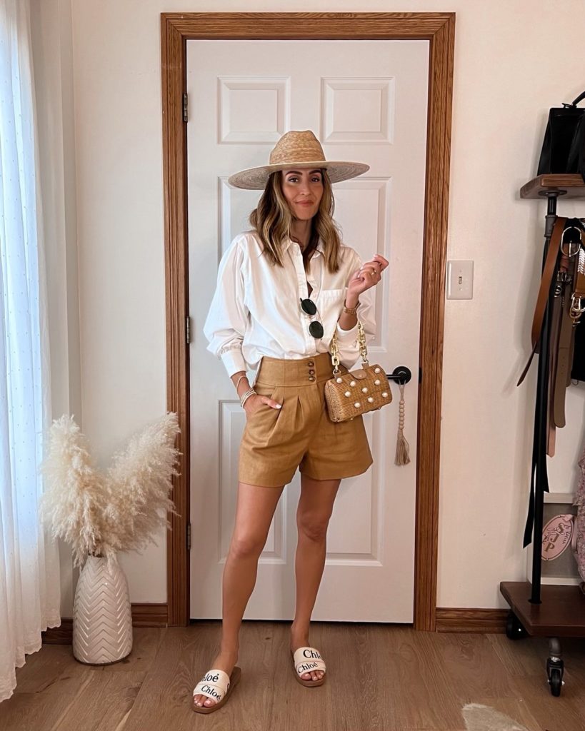 Karina wears Veronica Beard linen shorts with white button down and straw hat
