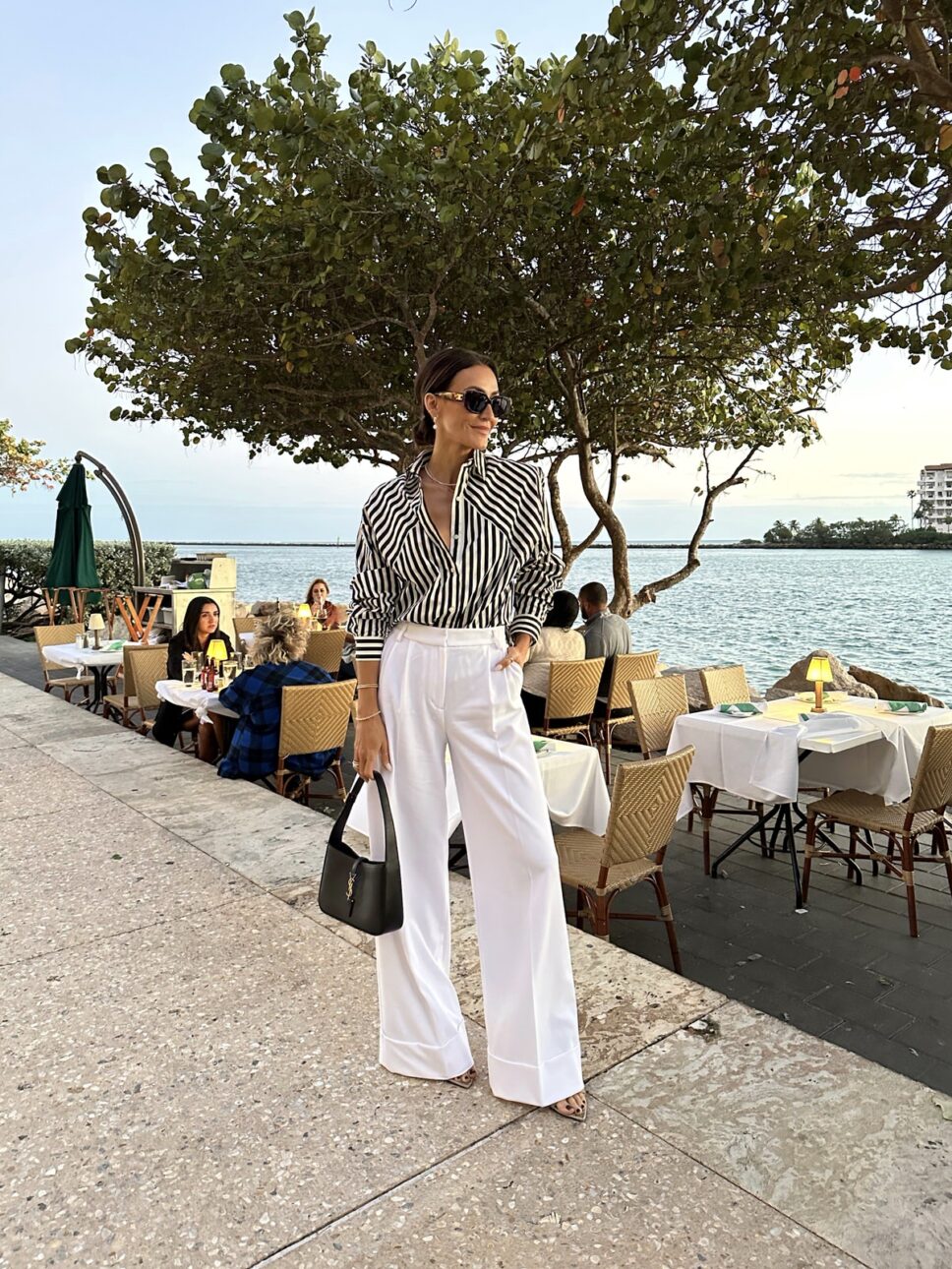 Karina wears Express striped button down with white trousers and YSL handbag and Celine sunnies