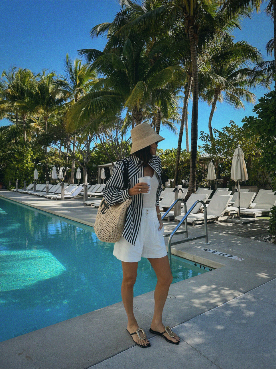 Karina Wears striped button down with Veronica Beard white linen shorts and anine bing beach tote