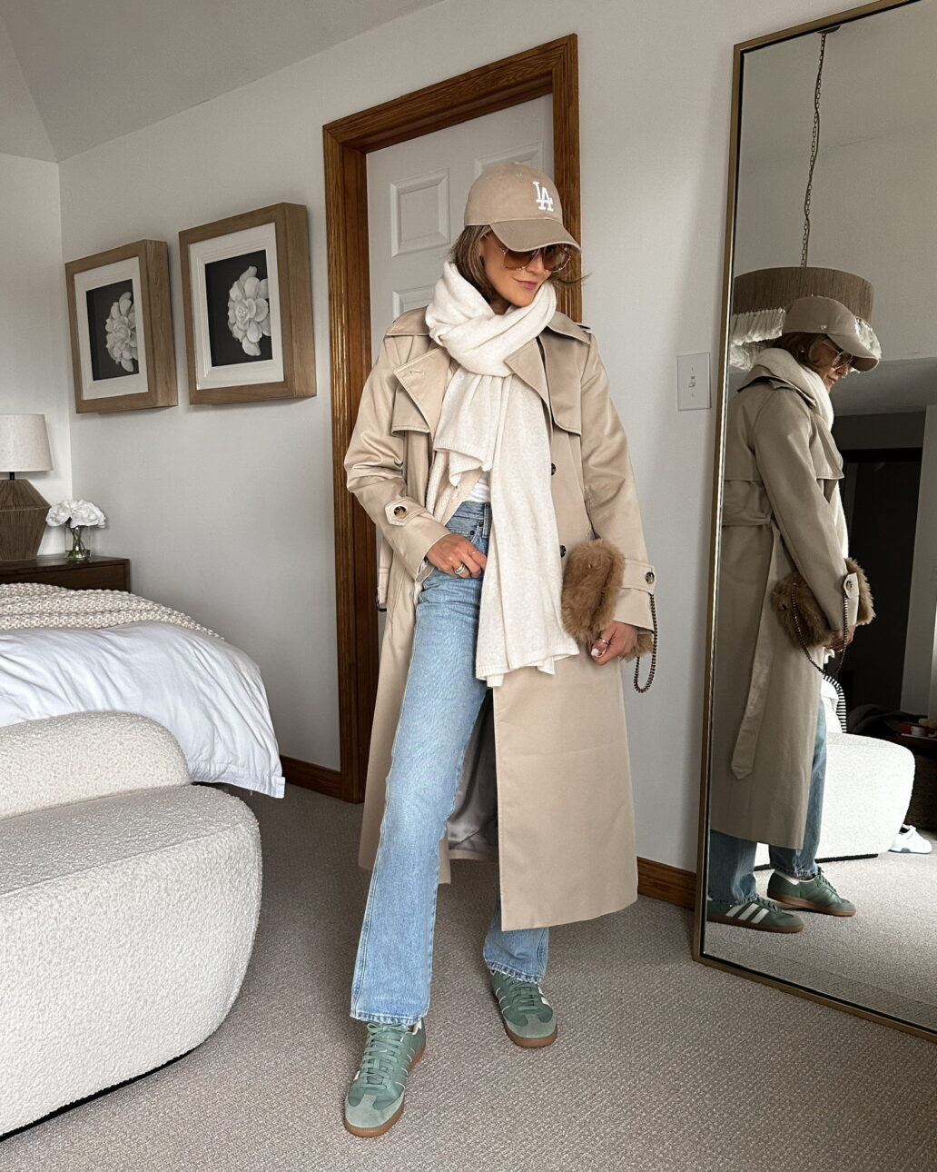 trench coat outfit with jeans, a scarf, a baseball cap, and sneakers