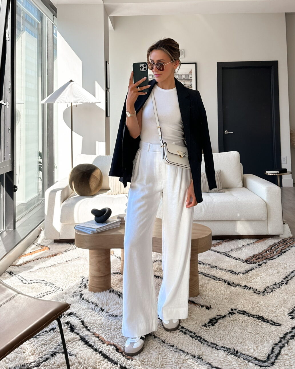 all white trouser outfit with a black blazer, white crossbody purse, and sneakers