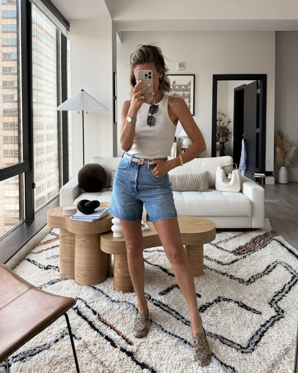 denim shorts outfit with a high neck tank top, belt, and loafers